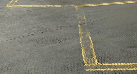 Faded yellow parking lot striping and worn markings on a commercial lot surface